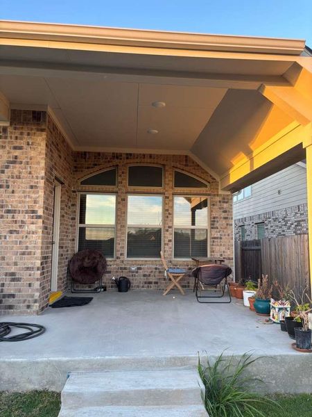 Covered back patio with brick exterior and concrete flooring
