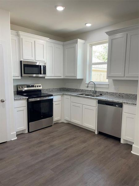 Kitchen with stainless steel range, sink, dishwashing machine, and white cabinetry