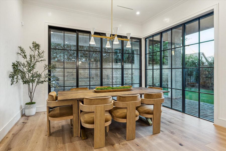 The dining room, framed by the home’s hallmark steel windows. A large table and chairs fit easily here for the perfect dinner party! Hardwoods and high ceilings evoke fancy dining ambience. A contemporary chandelier brings the space together.