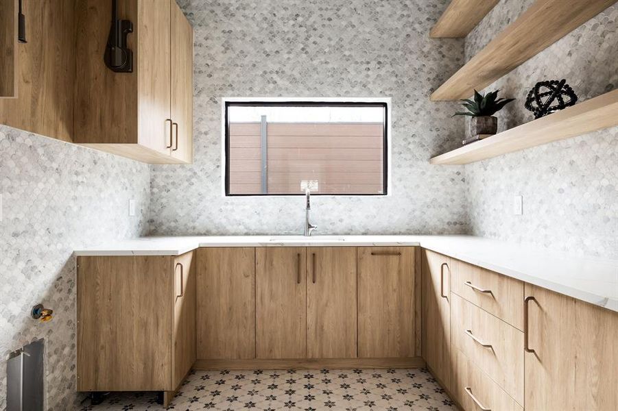 Kitchen with modern cabinets, light countertops, a sink, and open shelves