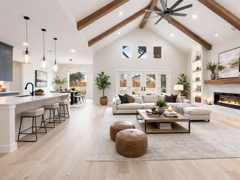 Living room with built in features, a glass covered fireplace, light wood-style floors, recessed lighting, and french doors