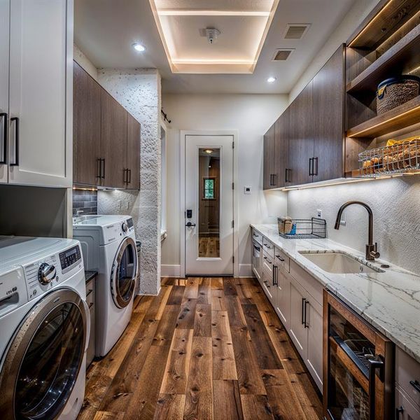 Laundry area featuring beverage cooler, a sink, dark wood-style floors, cabinet space, and separate washer and dryer