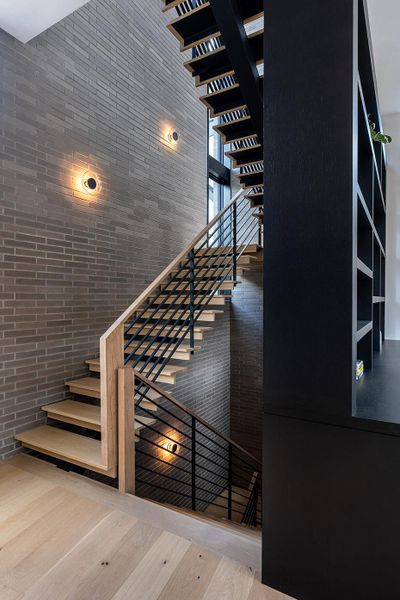 Modern industrial staircase featuring exposed brick and sleek wooden treads with metal railings. Modern industrial staircase featuring exposed brick and sleek wooden treads with metal railings.