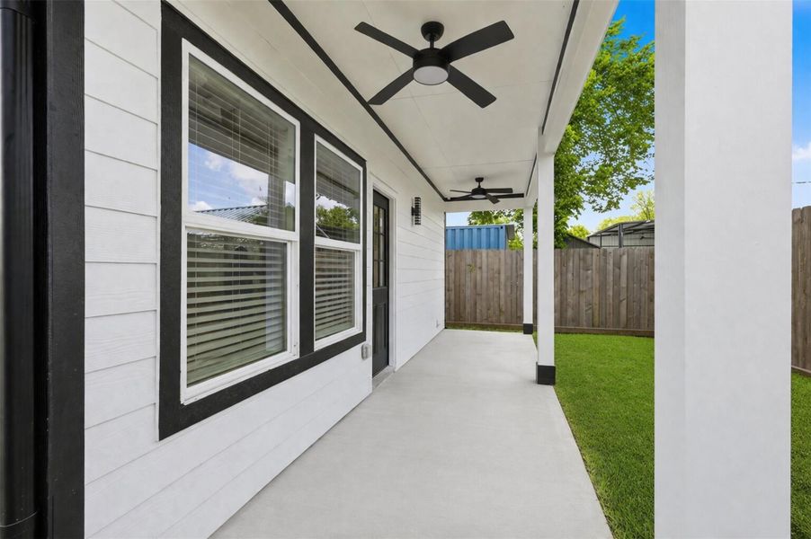 Covered back patio with ceiling fan, large windows, and backyard views — perfect for outdoor entertaining.