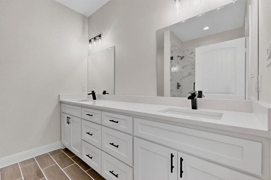 Bathroom featuring double vanity, a marble finish shower, and wood tiled floors Bathroom featuring double vanity, a marble finish shower, and wood tiled floors