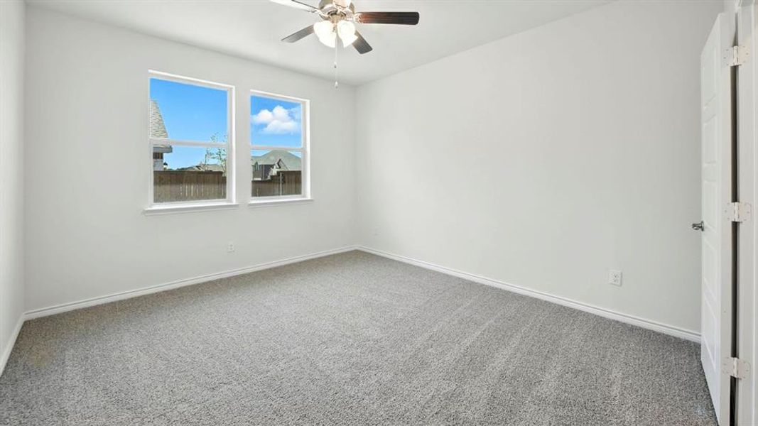 Carpeted empty room with baseboards and a ceiling fan
