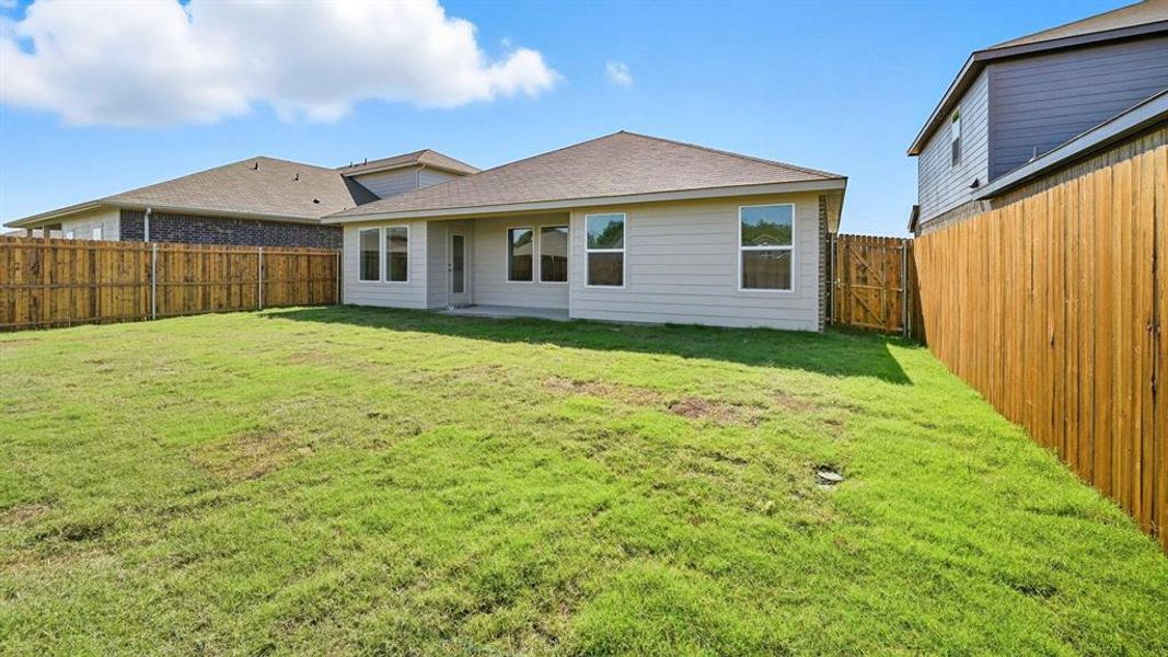 Rear view of house with a patio, roof with shingles, and a fenced backyard