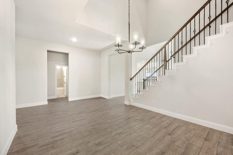 Open foyer with high ceilings, wood-look floors, chandelier, and staircase with iron balusters Open foyer with high ceilings, wood-look floors, chandelier, and staircase with iron balusters