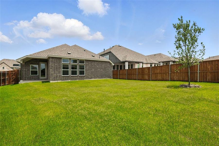 Rear view of house with a fenced backyard, brick siding, and roof with shingles Rear view of house with a fenced backyard, brick siding, and roof with shingles