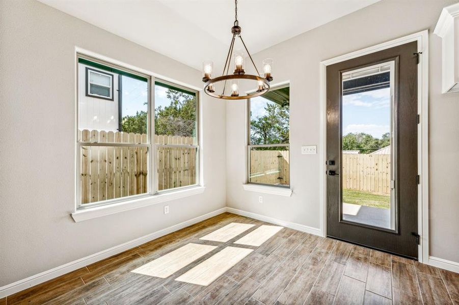 Unfurnished dining area with a wealth of natural light, hardwood / wood-style flooring, and a notable chandelier