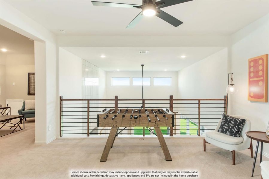 Upstairs game room loft with foosball table, metal railing overlooking lower level, and ceiling fan