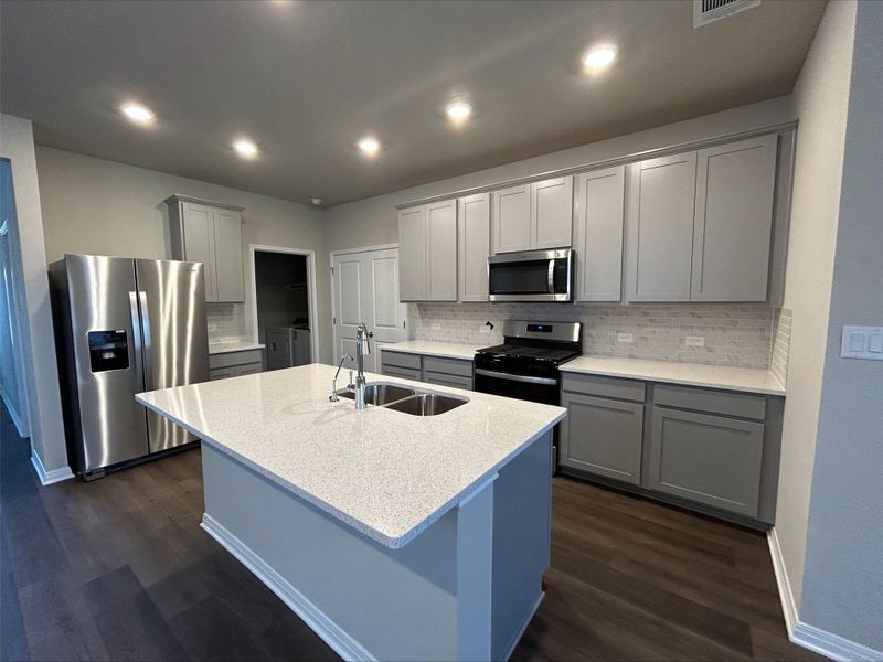 Kitchen featuring washing machine and clothes dryer, gray cabinets, stainless steel appliances, dark wood-style floors, and recessed lighting Kitchen featuring washing machine and clothes dryer, gray cabinets, stainless steel appliances, dark wood-style floors, and recessed lighting