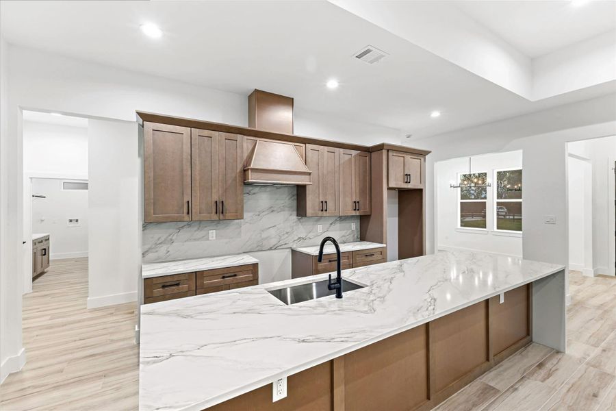 This modern kitchen features sleek wooden cabinetry, a spacious marble countertop island with a built-in sink, and stylish light fixtures, creating a bright and inviting space for cooking and entertaining. This modern kitchen features sleek wooden cabinetry, a spacious marble countertop island with a built-in sink, and stylish light fixtures, creating a bright and inviting space for cooking and entertaining.