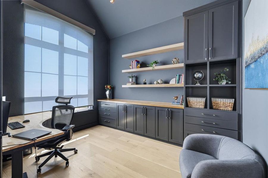Home office with light hardwood flooring, built-in cabinets, unique light fixture and lofted ceiling Home office with light hardwood flooring, built-in cabinets, unique light fixture and lofted ceiling