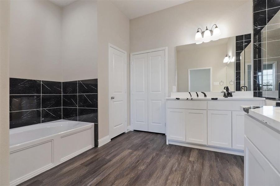 Bathroom with hardwood / wood-style floors, vanity, and a bathtub