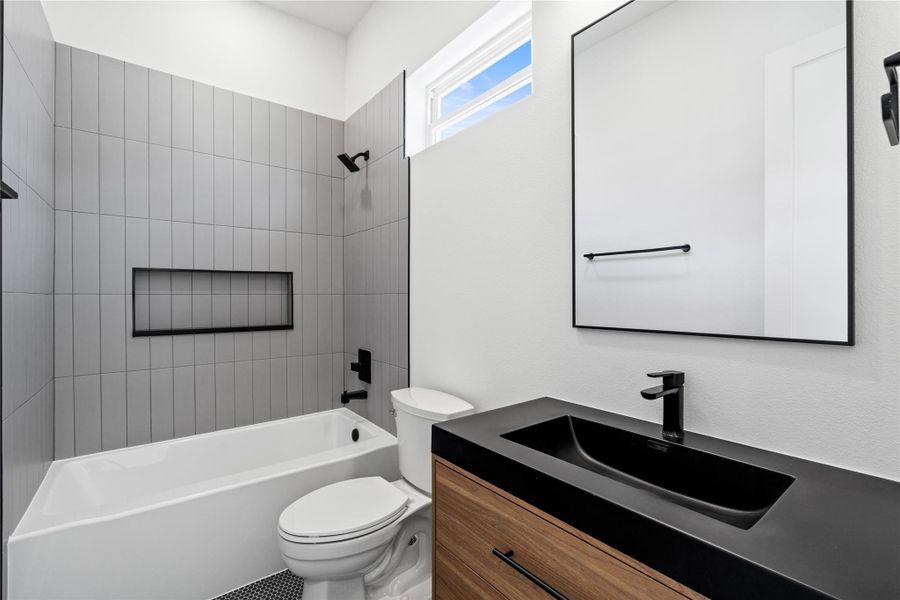 Crisp and composed, the secondary ensuite pairs a wood-veneer vanity with an integrated graphite basin and satin-black fittings. Vertically stacked tile and an elongated inset niche lend architectural order to the tub/shower, while a clerestory window introduces soft daylight—delivering a guest-ready bath that feels thoughtfully tailored. Crisp and composed, the secondary ensuite pairs a wood-veneer vanity with an integrated graphite basin and satin-black fittings. Vertically stacked tile and an elongated inset niche lend architectural order to the tub/shower, while a clerestory window introduces soft daylight—delivering a guest-ready bath that feels thoughtfully tailored.