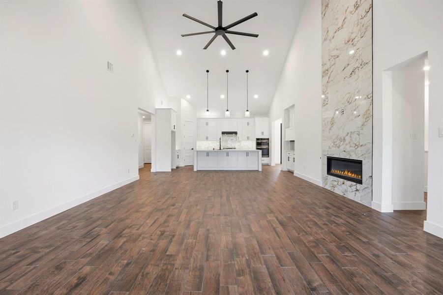 Spacious living area featuring high vaulted ceilings, wood-finish flooring, and recessed lighting Spacious living area featuring high vaulted ceilings, wood-finish flooring, and recessed lighting
