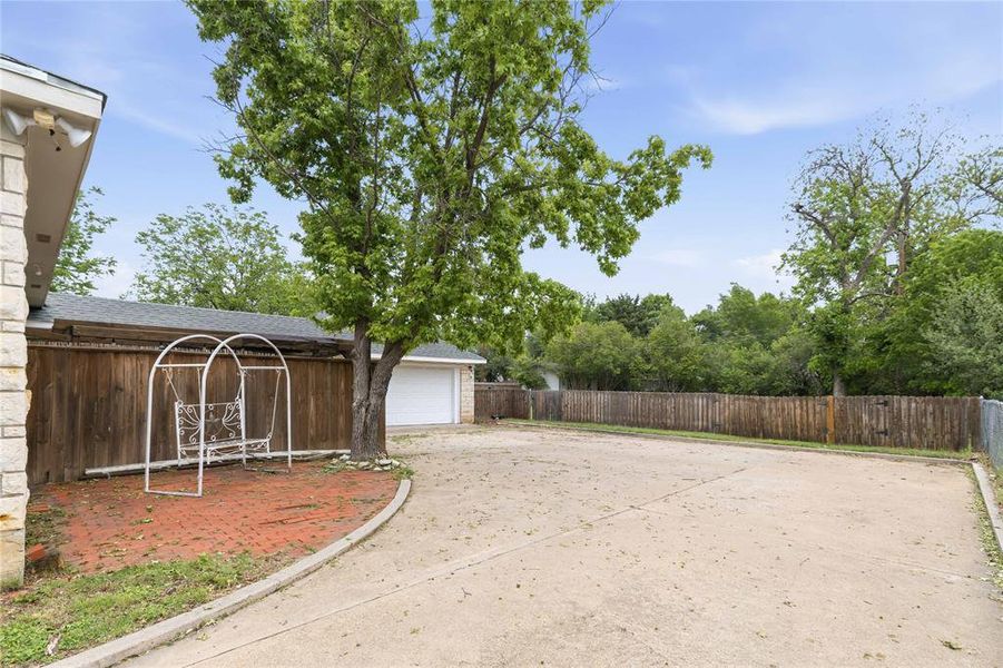 Expansive driveway with a detached garage featuring a white garage door Expansive driveway with a detached garage featuring a white garage door
