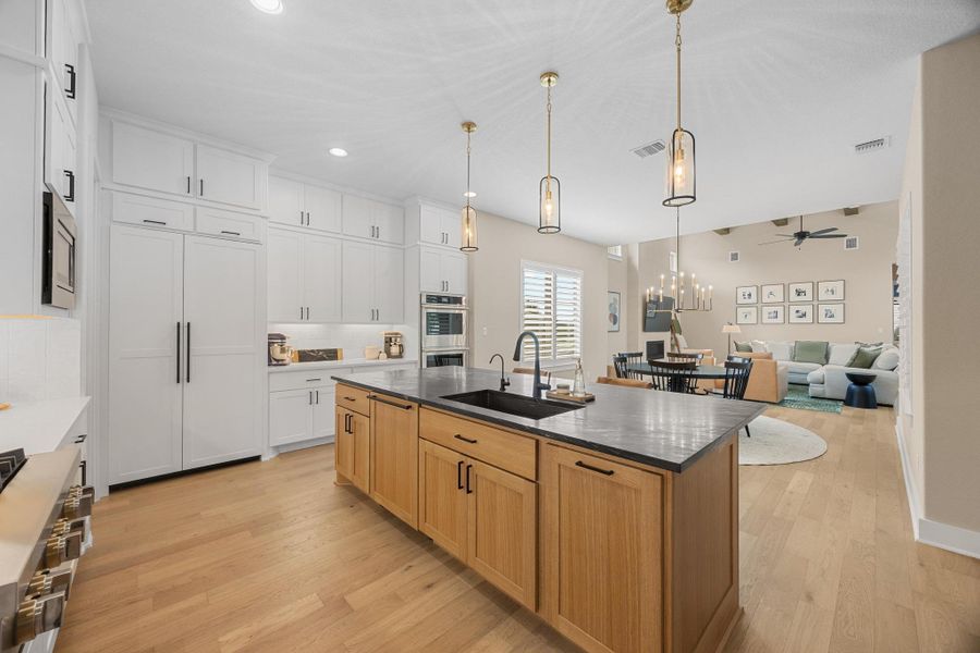 Kitchen featuring light wood-type flooring, ceiling fan, stainless steel appliances, a kitchen island with sink, and recessed lighting