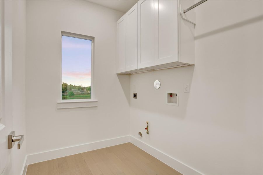Laundry room upstairs for convenience complete with upper cabinetry, hanging bar, and natural light.