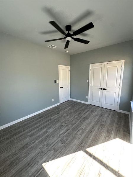 Unfurnished bedroom with a closet, dark wood-type flooring, and ceiling fan