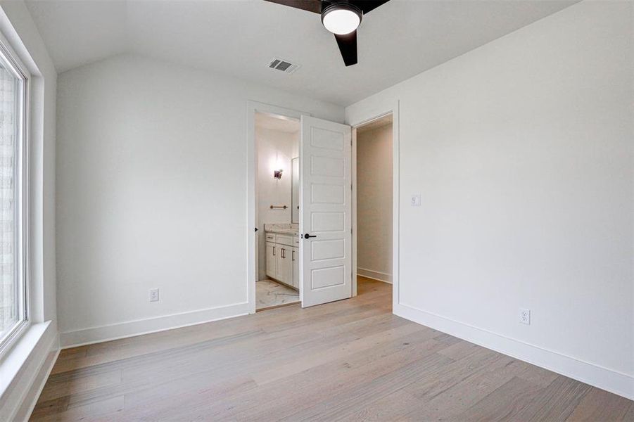 Unfurnished bedroom with ensuite bath, ceiling fan, and light hardwood / wood-style floors