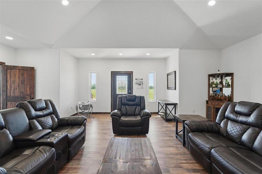Living area with wood finished floors, recessed lighting, and high vaulted ceiling Living area with wood finished floors, recessed lighting, and high vaulted ceiling