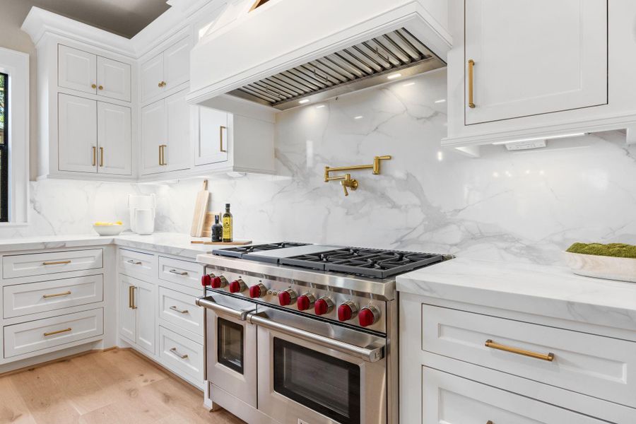 6-burner Gas Range w/ griddle & double oven w/Pot filler above mounted on the quartz backsplash. Under-cabinet lighting and tucked away outlets offer a clean uninterrupted backsplash