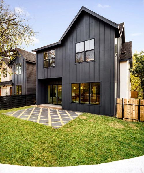 Back of house featuring board and batten siding, a fenced backyard, a patio area, and a shingled roof