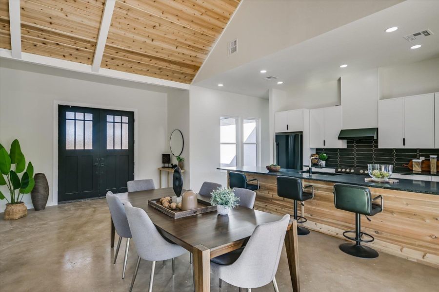 Dining room with high vaulted ceiling, concrete floors, recessed lighting, and wood ceiling