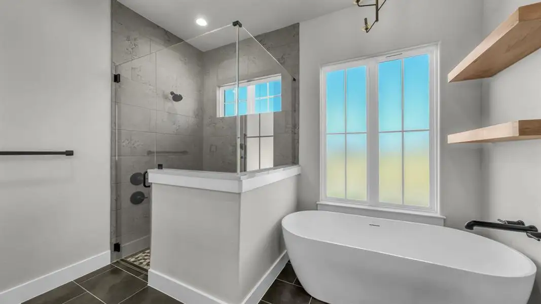 Bathroom featuring a freestanding tub, glass-enclosed shower with tiled walls, natural light from a multi-pane window, and light wood floating shelves Bathroom featuring a freestanding tub, glass-enclosed shower with tiled walls, natural light from a multi-pane window, and light wood floating shelves