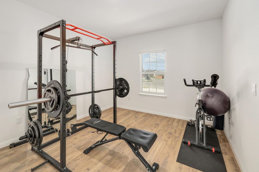 Versatile room featuring wood-finish flooring, white walls, and a window with horizontal blinds Versatile room featuring wood-finish flooring, white walls, and a window with horizontal blinds