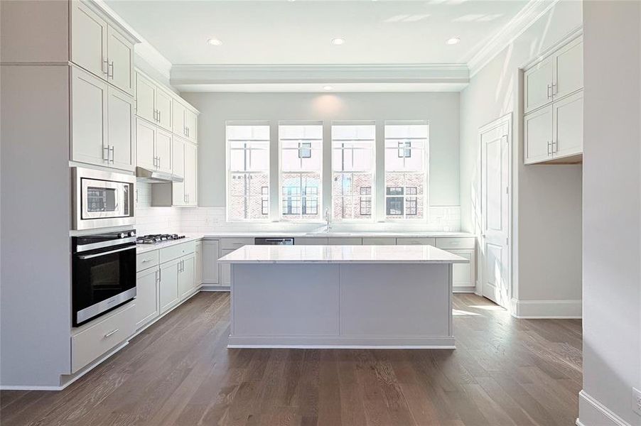 Progress photo of actual unit. Upgraded stacked cabinetry, warm neutral finishes, and abundant natrual light.