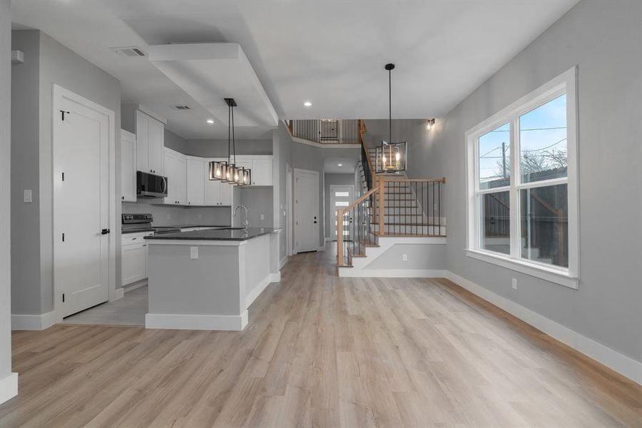 Kitchen featuring visible vents, light wood-style flooring, dark countertops, appliances with stainless steel finishes, and white cabinets