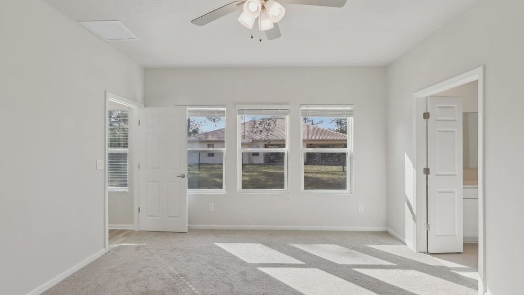 Experience luxury with plush carpet, abundant natural light, and elegant ceiling fan at Merritt, Palm Coast.