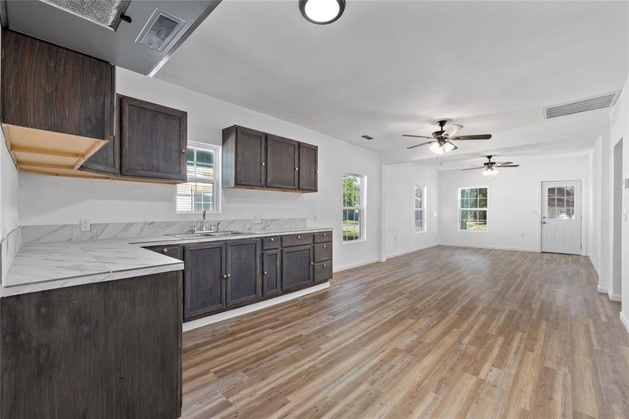 Kitchen featuring dark brown cabinets, light wood-style floors, exhaust hood, and ceiling fan Kitchen featuring dark brown cabinets, light wood-style floors, exhaust hood, and ceiling fan