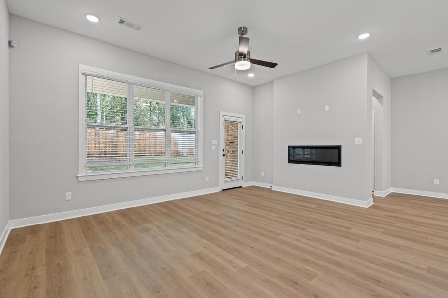 Unfurnished living room featuring a glass covered fireplace, recessed lighting, light wood-style flooring, and a ceiling fan