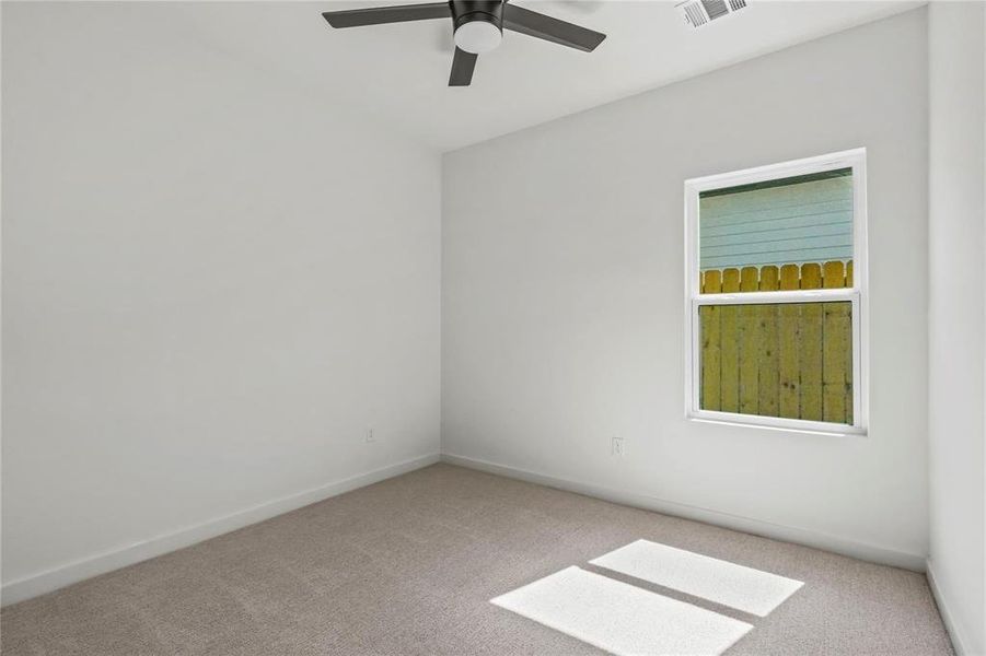 Empty room with carpet and a ceiling fan Empty room with carpet and a ceiling fan