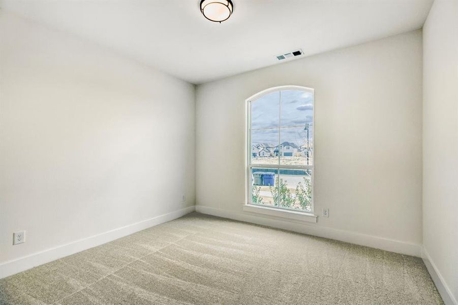 Room featuring a single arched window, light neutral walls, and a textured carpet