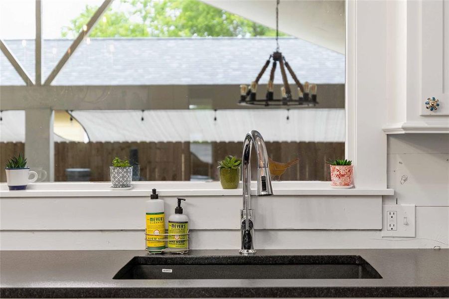 Kitchen sink featuring a chrome high-arc faucet, an undermount black sink, and a dark countertop