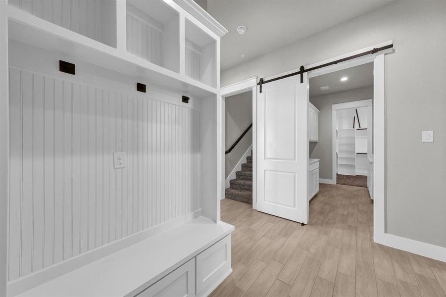 Mudroom with a barn door access to laundry room