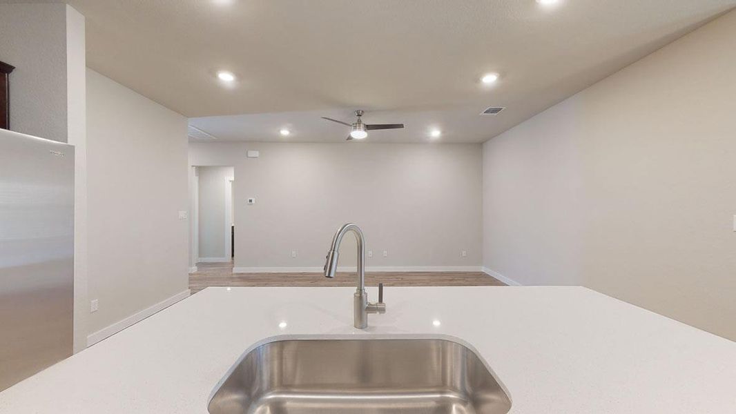 A well-appointed kitchen island with sleek quartz counters opens to an inviting living area. A well-appointed kitchen island with sleek quartz counters opens to an inviting living area.