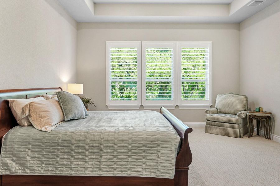 The spacious primary suite offers a quiet retreat overlooking the greenbelt behind the home. The spacious primary suite offers a quiet retreat overlooking the greenbelt behind the home.