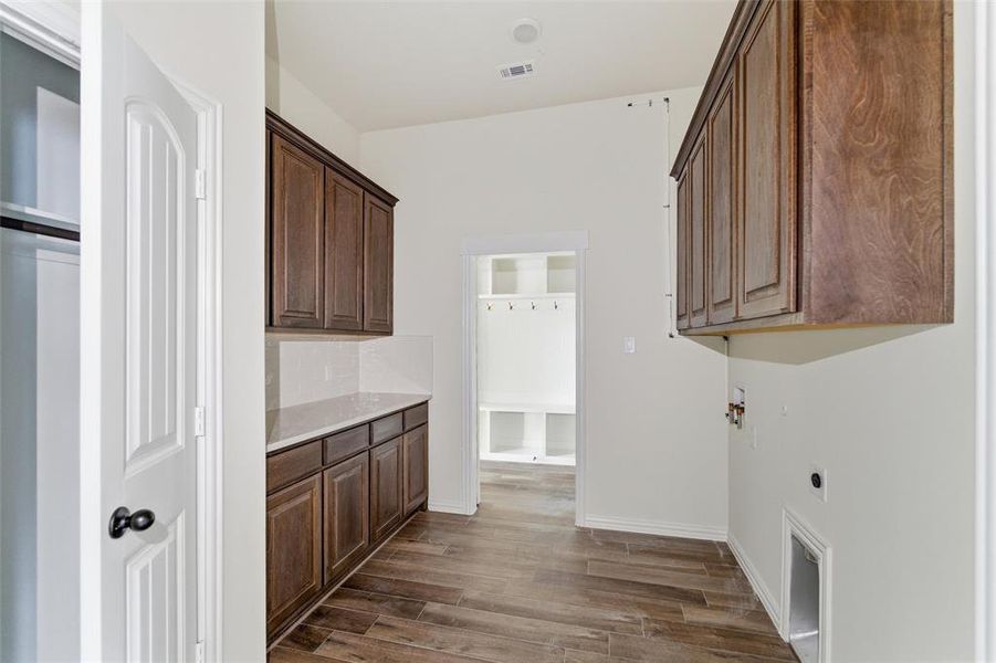 Laundry area featuring cabinet space, dark wood finished floors, hookup for an electric dryer, gas dryer hookup, and washer hookup