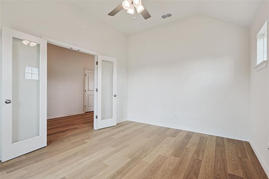 Unfurnished bedroom featuring lofted ceiling, ceiling fan, and light wood-type flooring