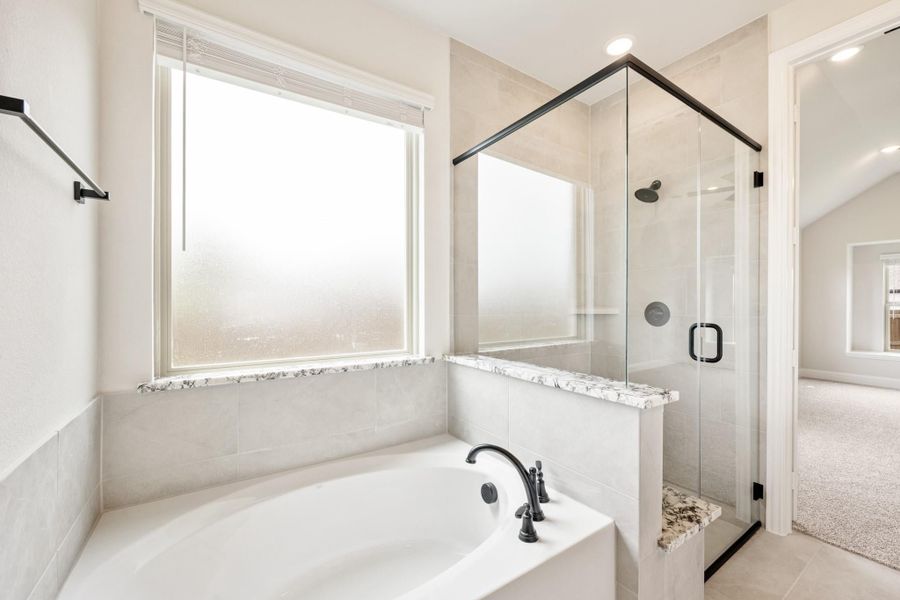 Master bathroom with soaking tub, glass-enclosed shower, tile walls, and black fixtures Master bathroom with soaking tub, glass-enclosed shower, tile walls, and black fixtures