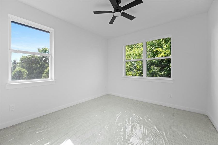 Carpeted empty room with plenty of natural light and ceiling fan