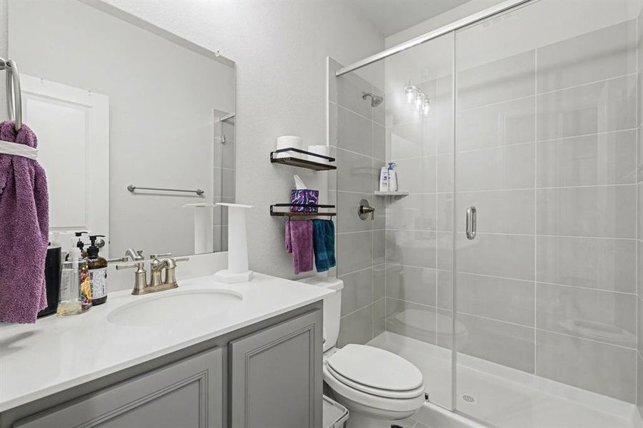 Bathroom featuring a single vanity with a gray cabinet, a white countertop, and a brushed nickel faucet