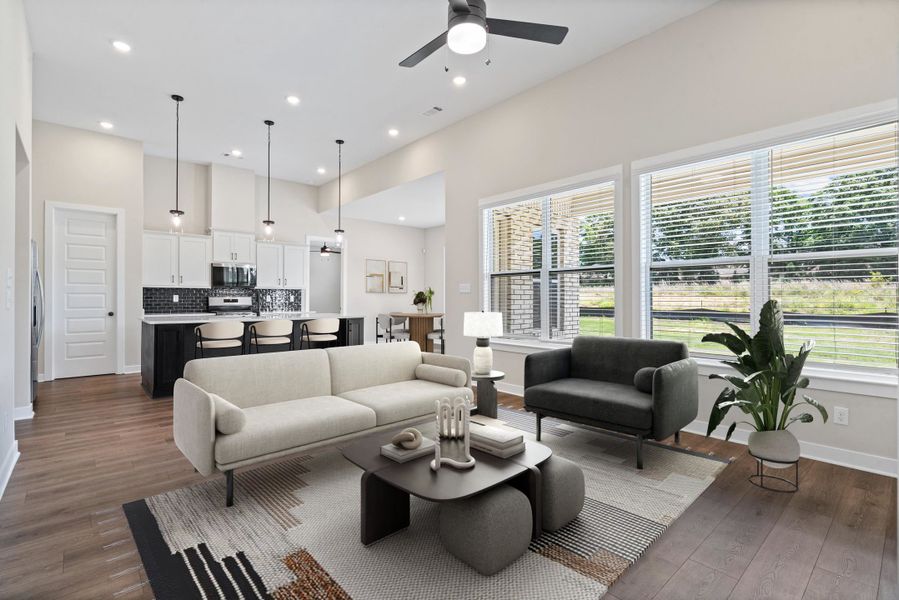 Open-concept living area featuring high vaulted ceilings, wood-finish flooring, and a contemporary ceiling fan Open-concept living area featuring high vaulted ceilings, wood-finish flooring, and a contemporary ceiling fan