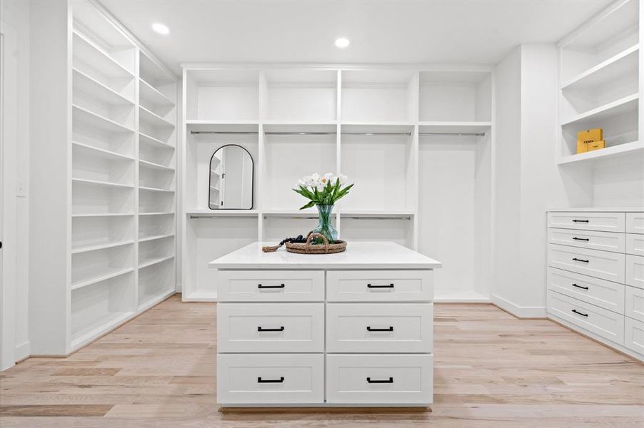 Oversized primary closet with center island with additional drawers.